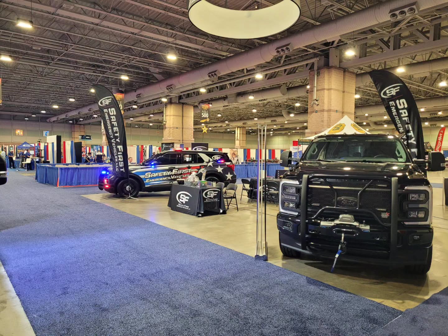 Aisle view of the SafetyFirst booth and demo vehicles on the expo floor.
