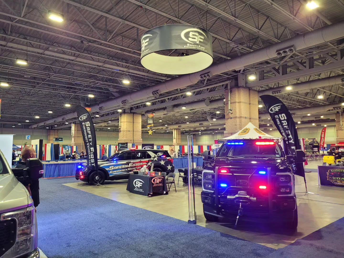 Wide view of the SafetyFirst Emergency Vehicles expo booth with both demo vehicles lit up.
