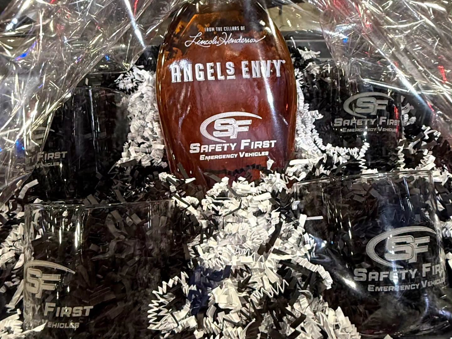 Close-up of the SafetyFirst enter-to-win gift basket featuring an Angel's Envy bottle and SF-branded rocks glasses.