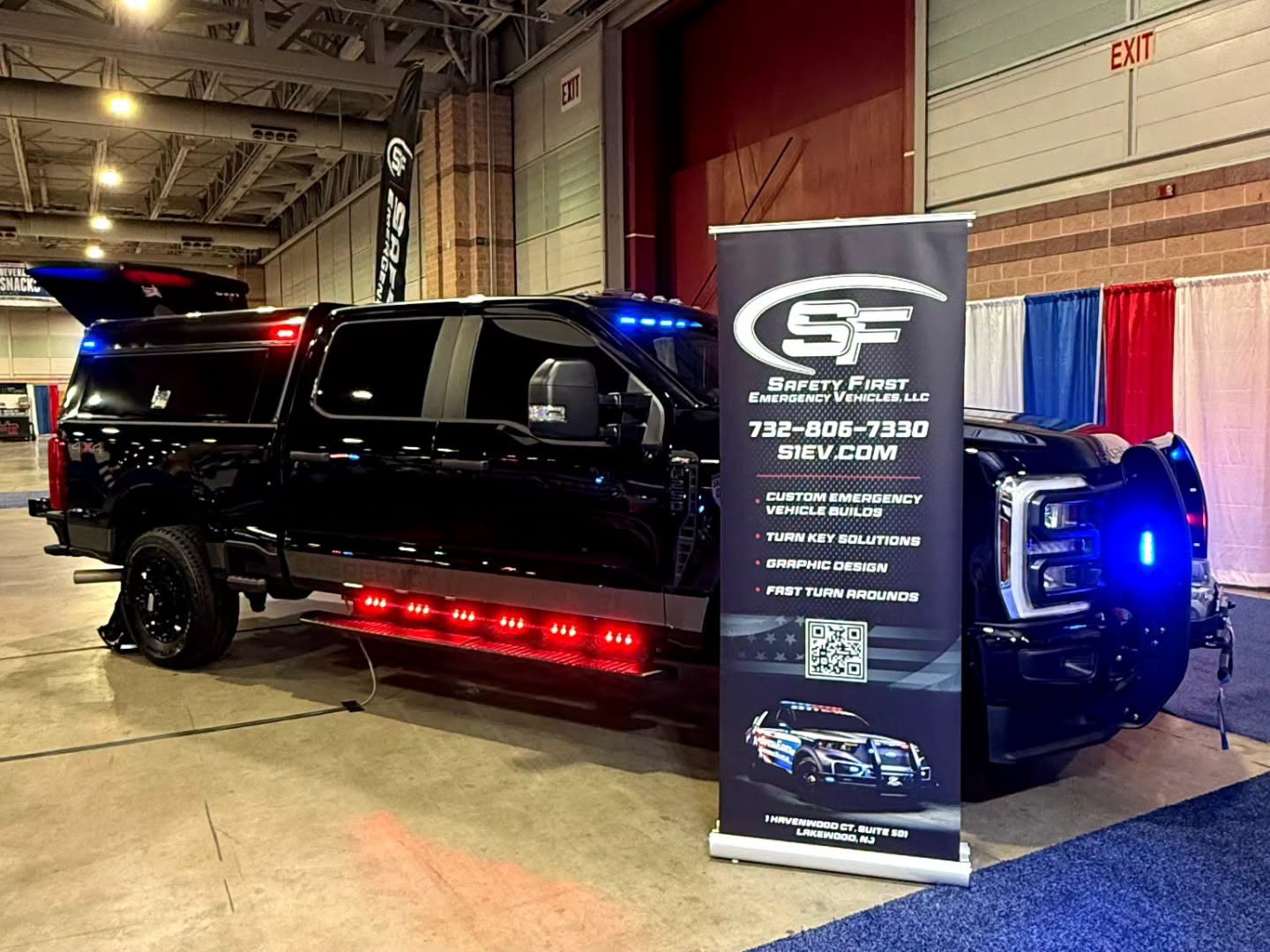 Side profile of the Ford Super Duty with LEER cap and red running-board lighting beside the SafetyFirst roll-up banner.